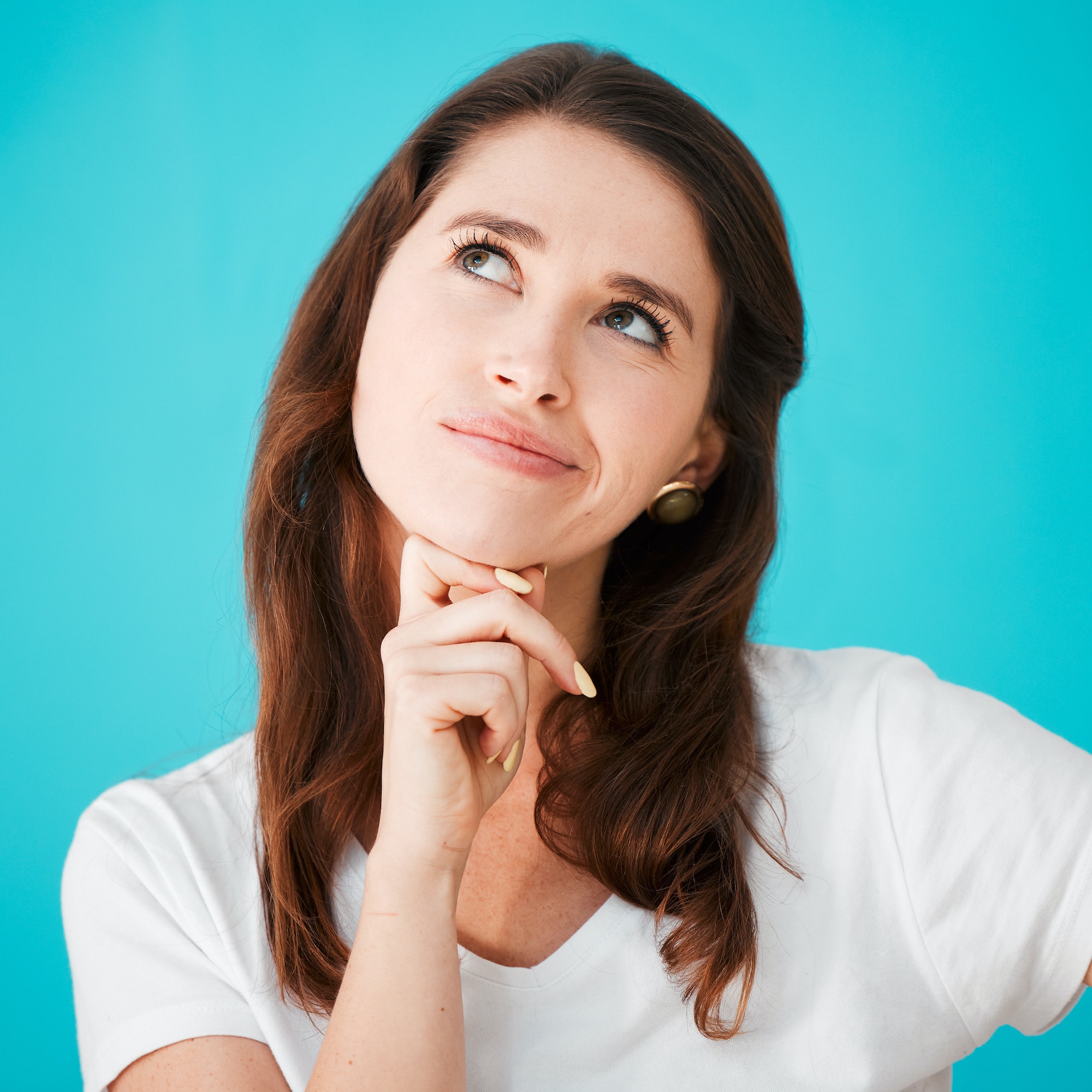 I wonder...Studio shot of an attractive young woman looking thoughtful against a blue background.